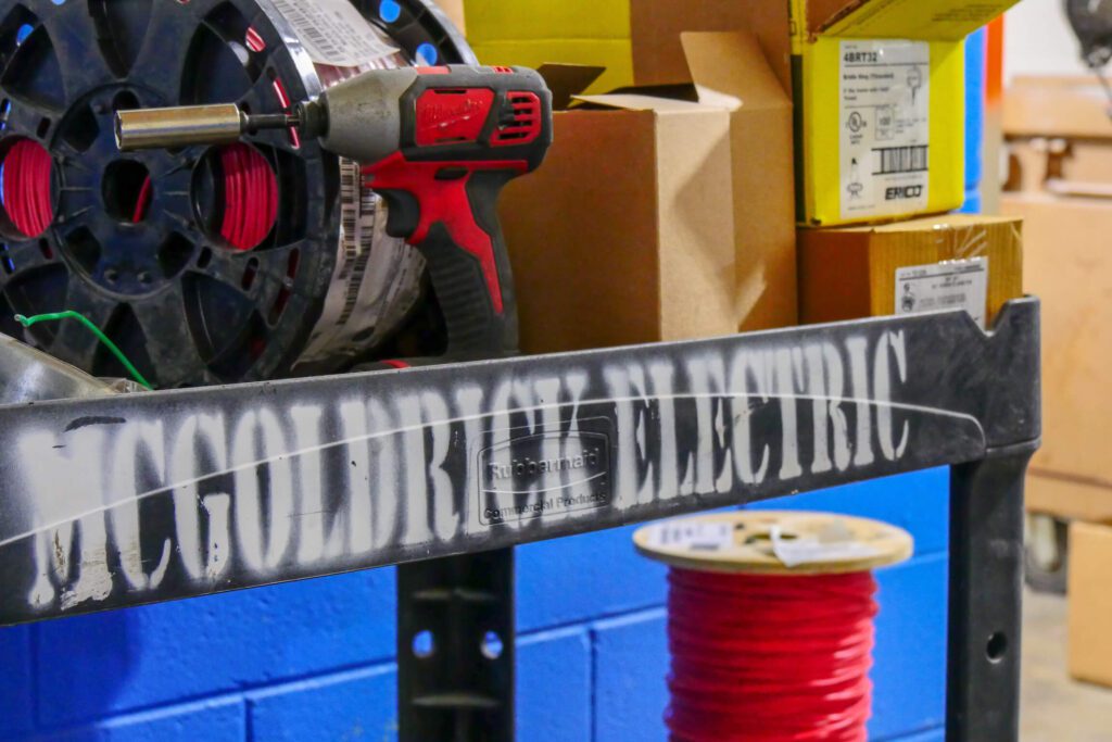 Bin labeled "McGoldrick Electric" full of commercial electric work supplies